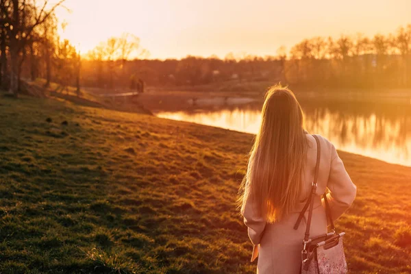 Uzun Saçlı Ceketli Kız Göle Bakıyor Sıcak Günbatımı Renkleri — Stok fotoğraf