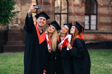 grup mutlu mezun öğrenciler cep telefonuyla selfie çekiyorlar. Diploma aldıktan sonra.