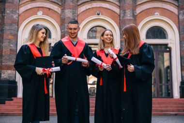 Üniversiteden başarılı bir mezuniyet, eğitim kavramı. Bir grup mutlu üniversite mezunu ellerinde diplomalarla, gülümsüyor..