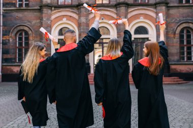 Arkadan bak. Bir grup öğrenci üniversiteye güle güle deyip, siyah cübbeli bir diplomayla ellerini kaldırdılar..