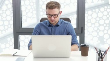 Bilgisayarda araştırma yapan işine odaklanmış bir girişimci. Bilgisayarı kullanan genç profesyonel bir erkek ofis masasında oturuyor. Modern teknoloji not defteri üzerinde çalışan meşgul bir işçi..