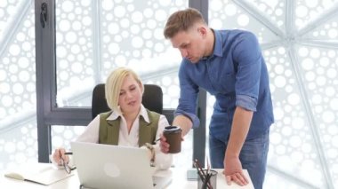 Masanın yanında duran takım elbiseli kendine güvenen bir şirket çalışanı şirket bilgisayar yazılımında bayan bir meslektaşa yardım ediyor. Genç işadamları proje değerlendirmesini deneyimli bir yöneticiyle tartışıyorlar..