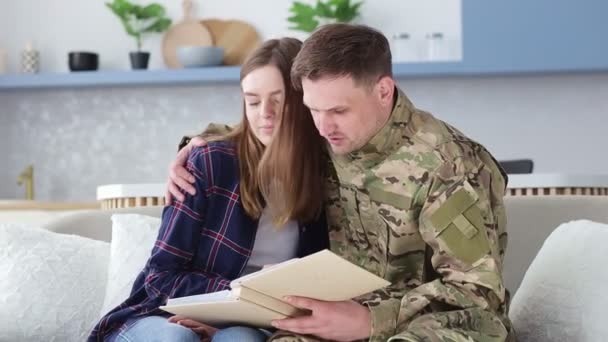 Man Hugs Woman While Sitting Couch Shows Album Photos Army — Stock Video