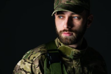 Sakallı bir adam kamuflaj üniforması içinde, üzgün bir yüzle, ailesini özlüyor..