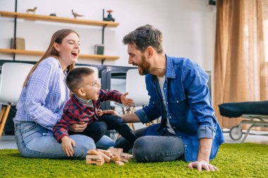Sevgi dolu bir aile yerde küçük bir çocukla küp oynuyordu, kule yıkıldı, babam üzüldü, elleriyle yüzünü kapadı..