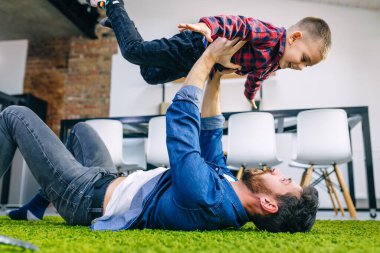 Şefkatli bir baba oğlunu kucağına alır, uzanmış ellerle uçuyormuş gibi yapar, mutfakta sıcak zeminde yatar, aile eğlenceli şeyler yapar.