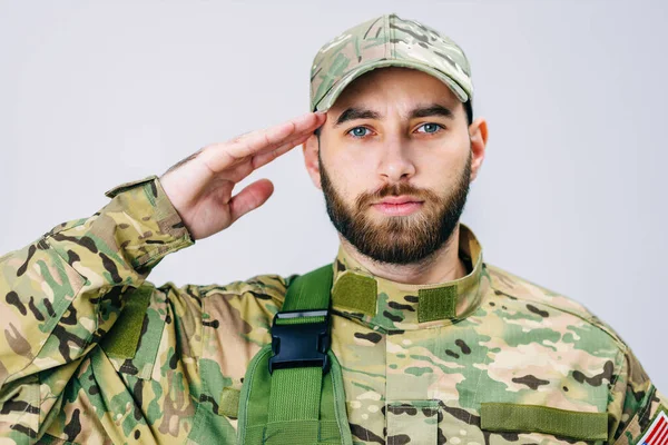 Kamuflaj üniformalı bir Amerikan askerinin portresi, selam veriyor, kameraya bakıyor. Asker saygı göstergesi olarak elini başına dayadı..
