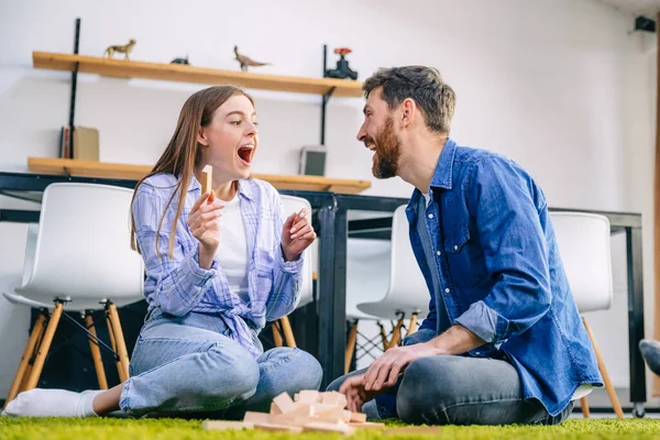 a cheerful couple sits on the floor, builds and destroys towers, spend their free time together.