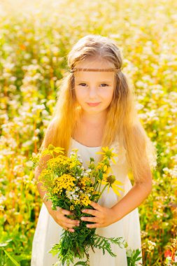 Tarlada çiçekli bir buket tutan hippi kılığındaki küçük kız..