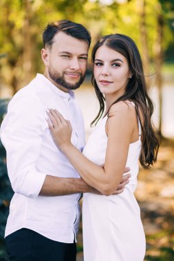 Çift erkek ve kadın parkta yürüyor ve sarılıyorlar..