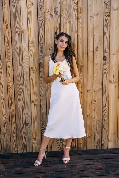 Uma Noiva Vestido Branco Está Contra Fundo Uma Parede Madeira — Fotografia de Stock