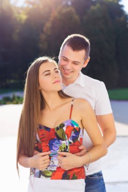 Genç adam şehir parkında yürürken kız arkadaşına arkadan sarılıyor..