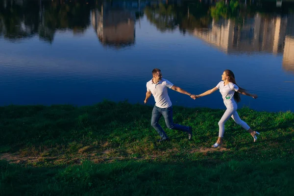 一个年轻人和一个女孩在湖边的森林里散步 快乐的夫妻牵着手 四处跑来跑去 玩得很开心 — 图库照片