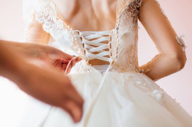 Nedime gelini düğün gününe hazırlar, düğmelerini ilikleyip elbisesini bağlar. Nedime, gelinin gelinliğinin arkasında bir fiyonk yapıyor, gelinin sabah toplantısı.