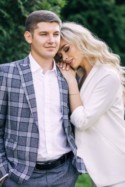 Gelin ve damadın yaz parkında yürüyüşü. Yeni evliler inzivaya çekildi. O ve o yeşil yaprakların arka planına karşı. Kız başını erkeğin omzuna koyar..