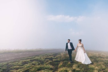 Gelin ve damat dağlarda yürüyorlar, doğa inanılmaz güzel, kalın bir sis..