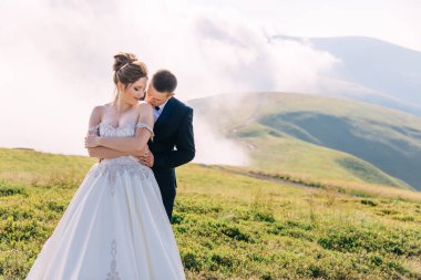Sıcak bir günde tarlada yürüyen mutlu gelin ve damat. Yeni evliler yazın doğada şefkatle sarılırlar..