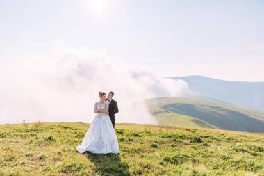 Yeni evliler tarlada durup birbirlerine bakıyorlar, düğün doğada, gelin ve damat sarılıyorlar..
