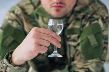 Kamuflaj üniformalı genç askerlerin elleri elinde bir şişe alkollü votka şişesiyle evde oturuyor. Askerlik sonrası depresyon, alkolizm ve bağımlılık