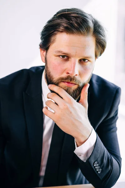 a handsome man with a beard with a stern look looks at the camera in the office. Business concept