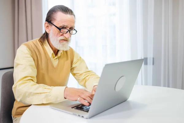 Przystojny Starzec Koncentruje Się Przy Laptopie Siedzącym Przy Stole Salonie — Zdjęcie stockowe