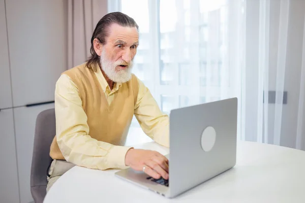 Zszokowany Zestresowany Staruszek Patrzy Laptopa Czyta Niesamowite Wiadomości Online Domu — Zdjęcie stockowe
