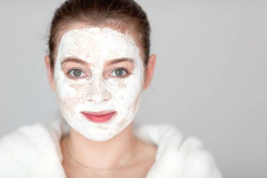 Yüzünde kil maskesi olan güzel bir kadın evde tek başına takılıyor.