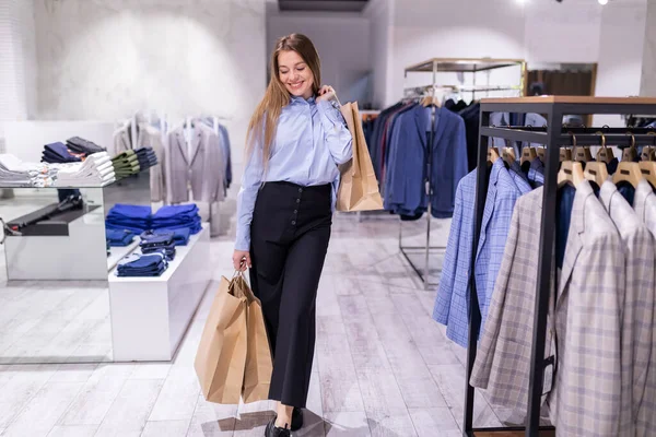 Positive Mädchen Mit Einkaufstaschen Papiertüten Zwischen Regalen Mit Kleidung Laden — Stockfoto