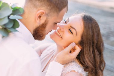 Birbirine bakan yeni evli çiftlerin yakın çekimi. Damat karısının yüzüne dokunur.