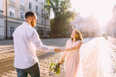 Güneşli bir sokakta poz veren genç bir çift. Güzel bir kadın ve yakışıklı erkek arkadaşı sokaklarda yürüyor..