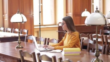 Üniversite öğrencisi dizüstü bilgisayar kullanıyor, uzaktan öğrenmeyi internetten denetliyor, bir seminerde not defteri tutuyor.