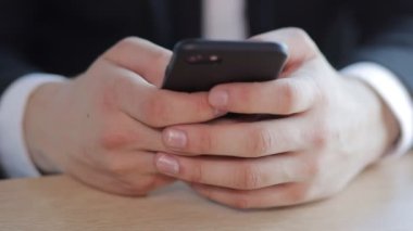 Genç adam ödev yaparken akıllı telefon kullanıyor. Bir adam cep telefonundan mesaj göndermeyi öğrenir. Yakın plan.