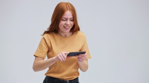 Αστείο Κορίτσι Κόκκινα Μαλλιά Που Παίζει Παιχνίδια Στο Κινητό Τηλέφωνο — Αρχείο Βίντεο