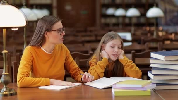 教室の机に座っている若い先生と小学生 家庭教師は生徒に宿題を説明する — ストック動画