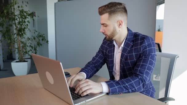 ノートパソコンに入力するビジネス女性に焦点を当て 電話に気を取られて机に座っているコンピュータを使用して若いプロの男性 現代のテクノロジーノートパソコンで働く忙しいフリーランスの労働者 — ストック動画