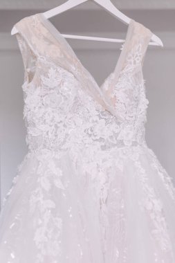 Beyaz duvarın arkasında asılı gelinlik. Değerli taşları olan güzel bir korse