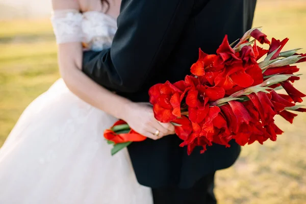 Krásná Kytice Červenými Květy Rukou Nevěsty Novomanželé Objímají Procházce — Stock fotografie