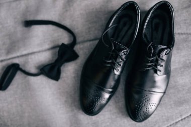 Gri arka planda şık erkek ayakkabıları papyonun yanında