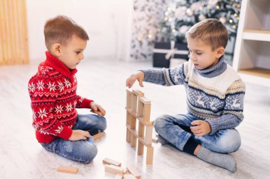 İki sevimli kardeş ahşap yapı taşlarıyla kule modelini tamamlıyor. Çocuk evde ısıtmalı katta otururken eğitim oyunları oynuyor. Güvenli konfor konsepti