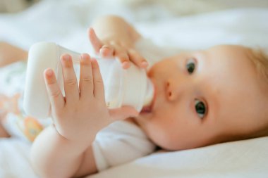 Küçük şirin beyaz bebek şişeden süt içiyor.