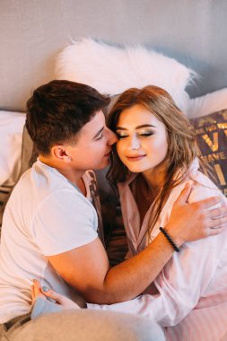 Yatakta yatan bir adamla bir kızın üst görüntüsü ve gözlerini kapatmaları. Pijamalı çift.