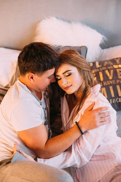 Yatakta yatan bir adamla bir kızın üst görüntüsü ve gözlerini kapatmaları. Pijamalı çift.