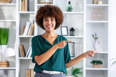 Afro-Amerikalı kadın gülümseyen yüzüyle iki elini de sağ tarafa doğrultuyor. Gülümseyen profesyonel iş Afro-Amerikan kadın fotokopi alanı gösteriyor