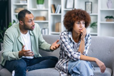 Oturma odasındaki koltukta oturan genç çift, anlaşmazlık yüzünden kavga eden erkek kadına bağırıyor, kadın kocasının psikolojik tacizine uğruyor.