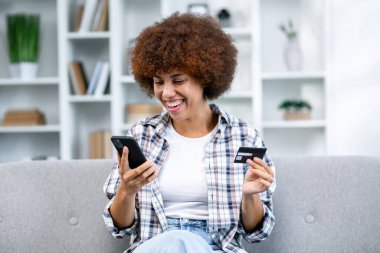 İnternetten alışveriş yapan bir kadın. Güvenli mobil bankacılık. Gülümseyen bayan müşteri cep telefonu kredi kartı sahibi akıllı telefonuyla alışveriş yapıyor. Mutlu genç kadın kolay ve hızlı para transferinin keyfini çıkar.