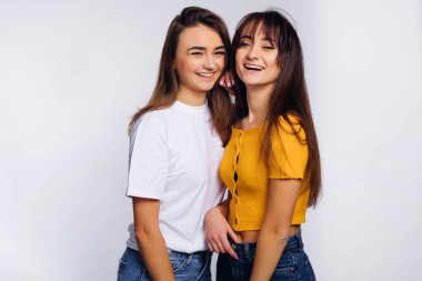 Şık giyinmiş kızlar gülümser ve beyaz arka plandaki kameraya bakarlar. makyaj.