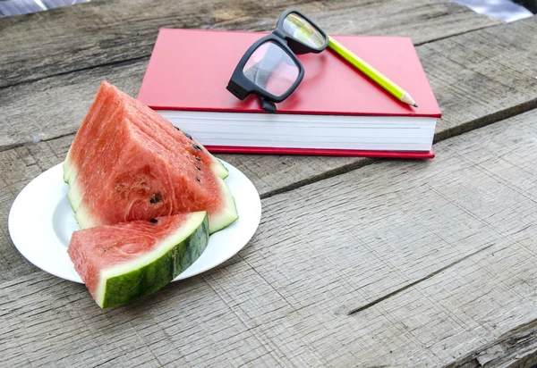 Watermeloen met rode boek over houten tafel — Stockfoto