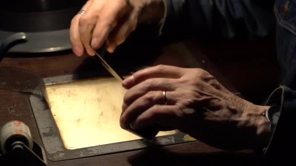 Człowiek siedzący przy stole montażowym trzyma film w rękach. — Wideo stockowe