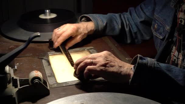 L'uomo seduto al tavolo di montaggio tiene il film nelle sue mani e lo dispiega — Video Stock