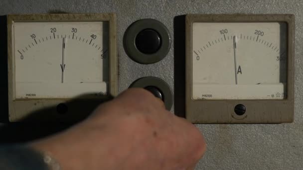 Ein Mann drückt einen Knopf und der Pfeil des Voltmeters geht nach unten — Stockvideo